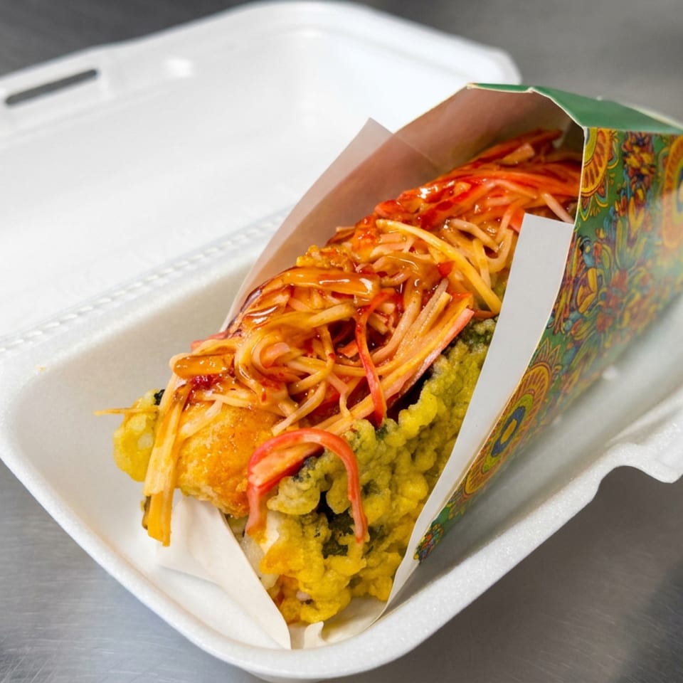 Loaded fried snack topped with spaghetti, red sauce, and shredded vegetables in a colorful paper tray.